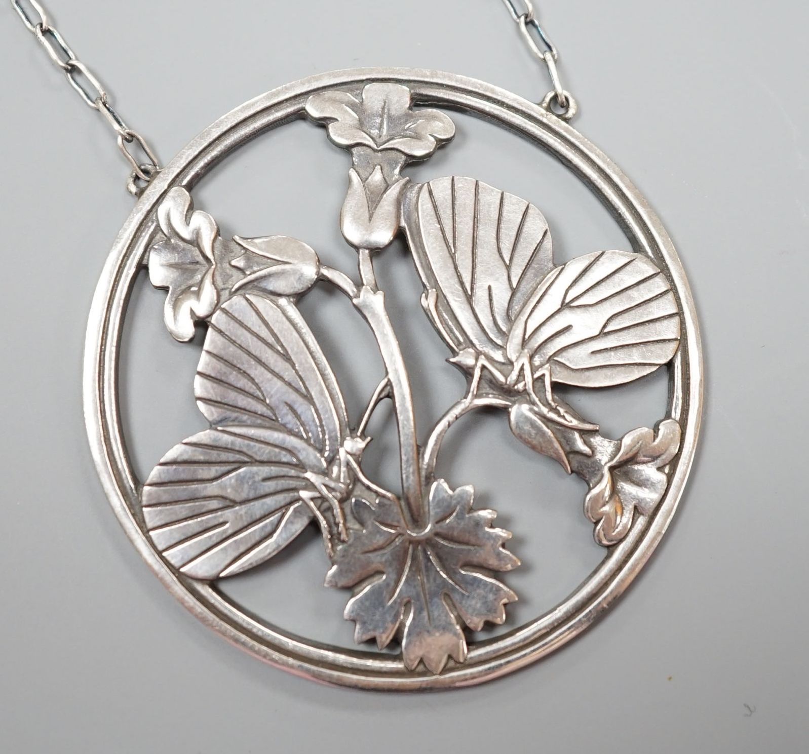 A George Jensen (designed by Arno Malinowski) sterling 'twin moth amid foliage' circular pendant necklace, no. 105, pendant diameter 51mm, chain 54cm.
